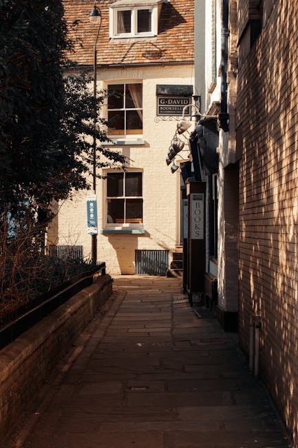A close-up view of a light blue brick house on King Street, Teddington, showing three white-framed windows and two blue doors at the ground level. The larger door on the right has a small window panel